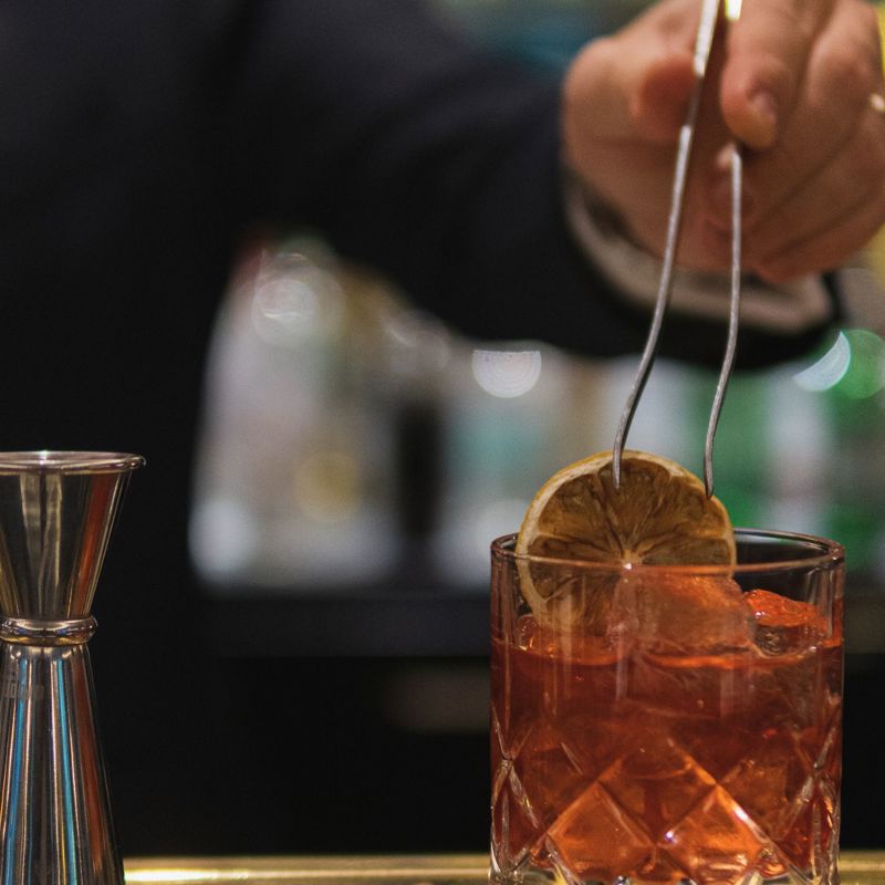 Man adding dehydrated orange to a cocktail