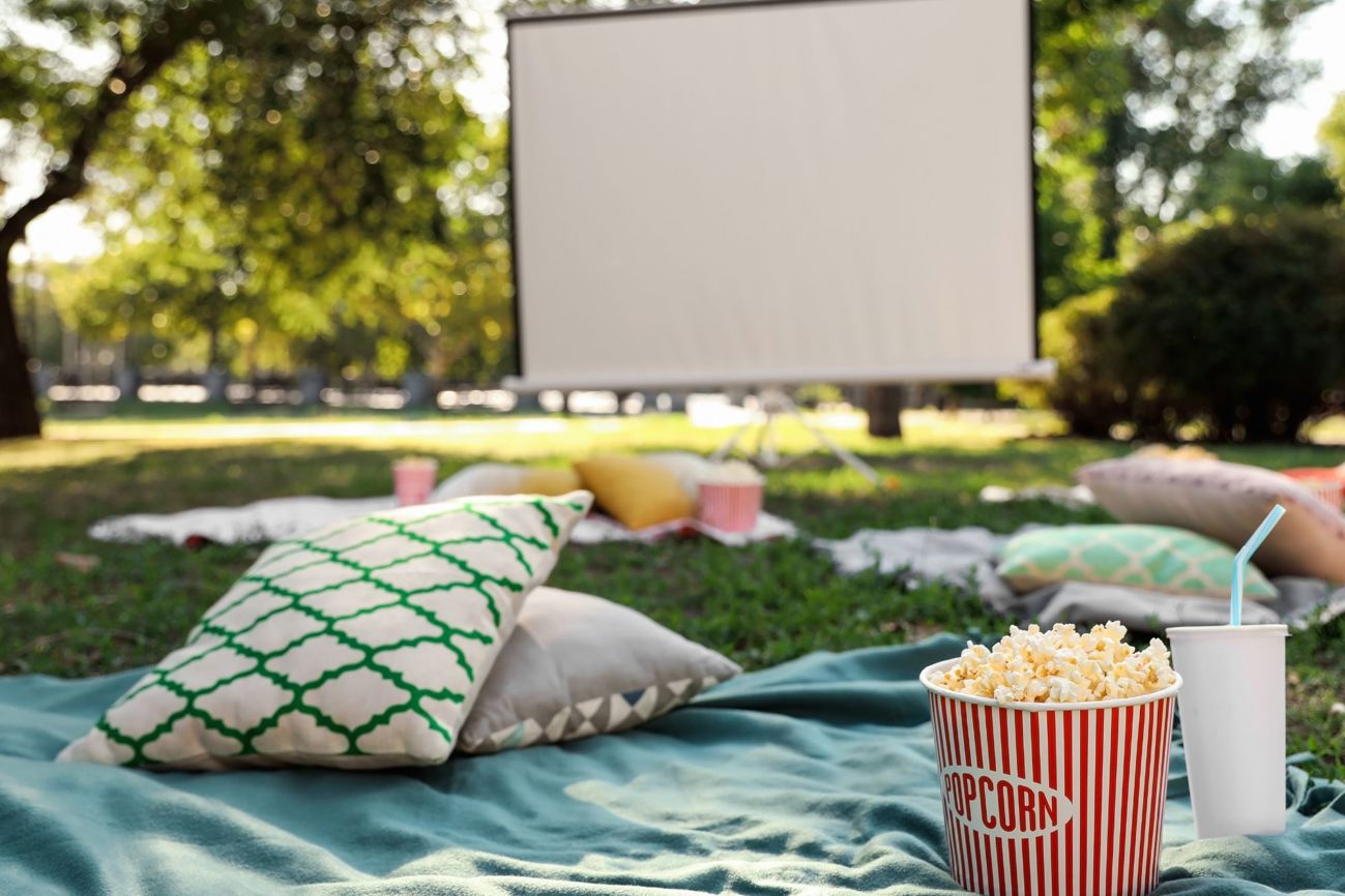 open air cinema screen with box of popcorn, cushions on a rug