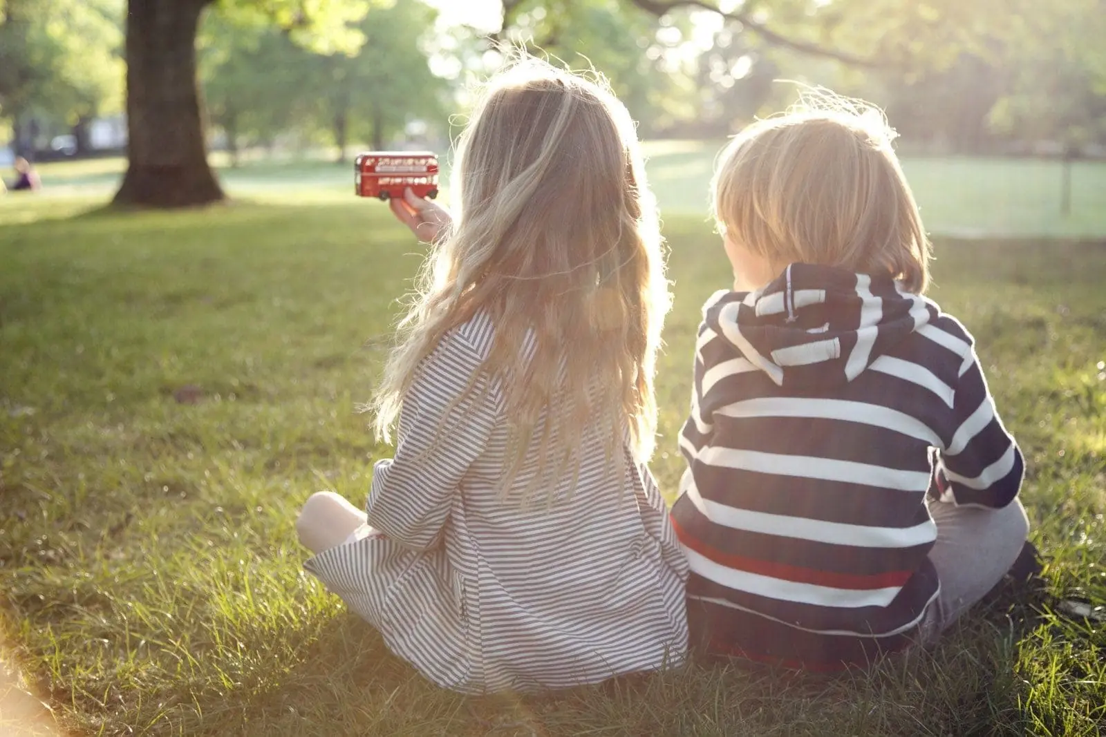 Two kids sitting in the sun at Green Park, near the luxury 5 star hotel The Athenaeum