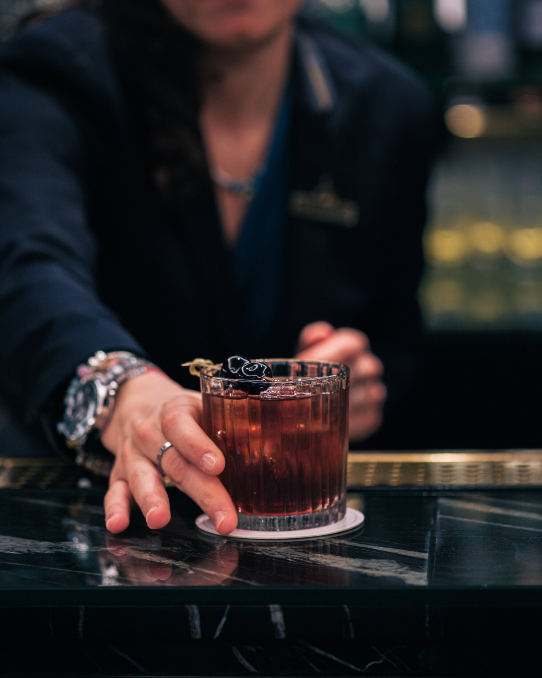 Server handing a drink to a guest in the bar at the athenaeum hotel